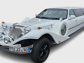 Excalibur Oldtimer Stretchlimousine in Weiß mit rotem Teppich und einer Sektflasche